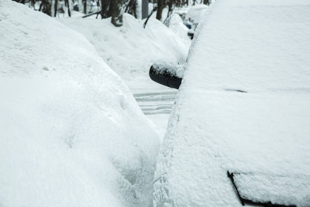 d’énormes congères de neige dans la rue avec des voitures enneigées garées, un véhicule sans caractéristiques gelé par les intempéries hivernales. - featureless photos et images de collection