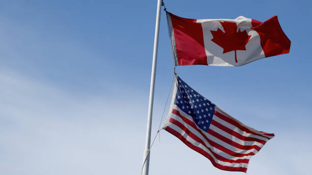 istock canada and usa flags fluttering in the wind on blue sky copy space blue sky background 1478427960