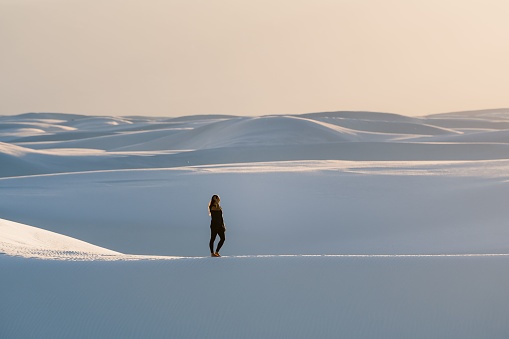 A female in black clothing with one hand on her hair at White Sands National Park