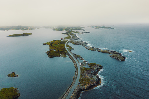 Drone high-angle photo of famous idyllic highway above sea and islands with group of cars driving during sunset in Western Norway