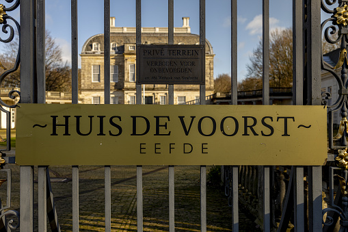Zutphen, Netherlands – January 12, 2021: Plaque on entrance gate of Huis de Voorst castle in the foreground and the monumental stronghold in the background