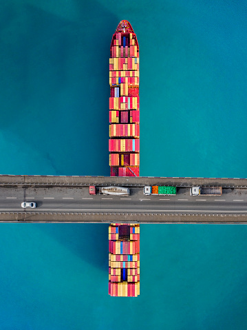 Container Ship Beneath Bridge. Aerial view of a cargo ship passing beneath a suspension bridge.