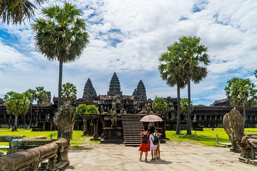 Angkor Wat, Cambodia – August 04, 2022: The temple towers of the largest religious temple complex Angkor Wat in Cambodia, with tourists visiting it on a sunny day