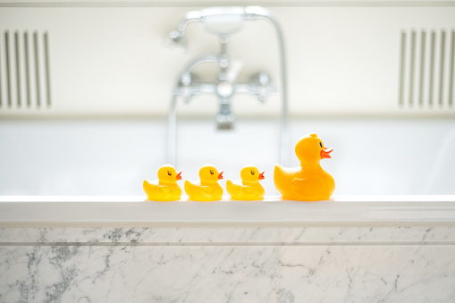 A selective focus shot of cute yellow rubber bath ducks in a row in a bathroom