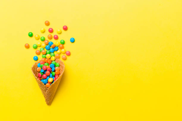 istock waffle cone full of assorted traditional candies falling out on colored background with copy space. Happy Holidays sale concept 1478437096