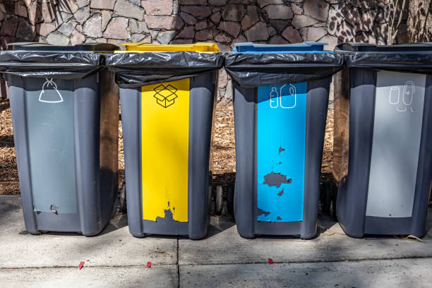 istock Four garbage cans for recycling against stone wall in background 1478437754