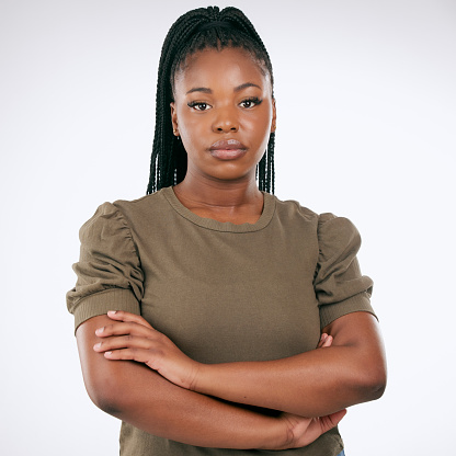 Black woman, arms crossed and standing isolated on gray background for confident profile or empowerment. Portrait of African American female model with serious face for leadership or management