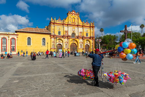 Balloon seller on the main square of San Cristobal de las Casas with its colorful Cathedral, Chiapas, Mexico.