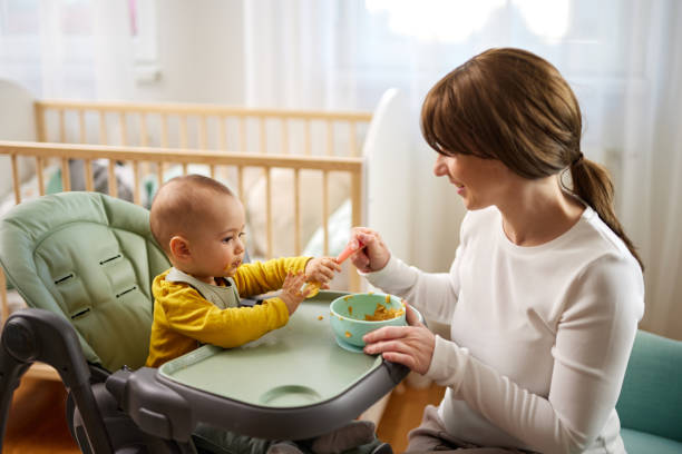 istock Mother spoon feeding her baby son at home 1478442796
