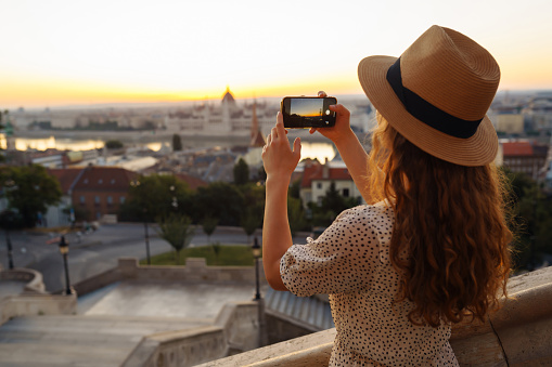 Tourist woman shoots a city landscape at dawn on a smartphone. Travel in Europe.