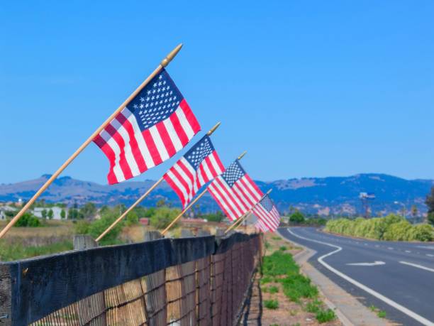 istock USA flags flattering on a wall next to a highway with mountains in the background 1478445976