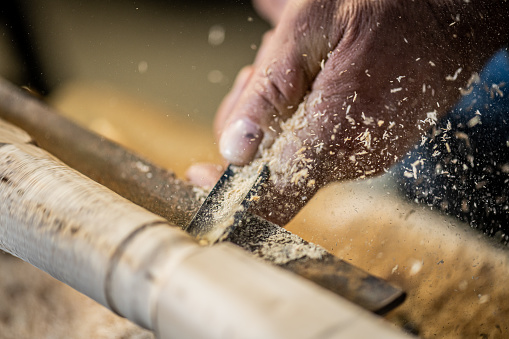 Close-up of man carpenter's hand craft wooden plank in workshop.