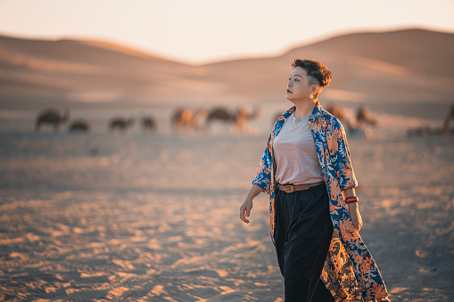 Asian Chinese solo female traveler walking in Sahara Desert in the morning