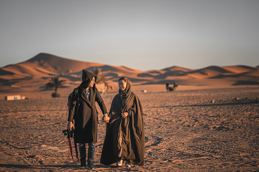 Asian Chinese Couple holding hands walking in Morocco Sahara Deser