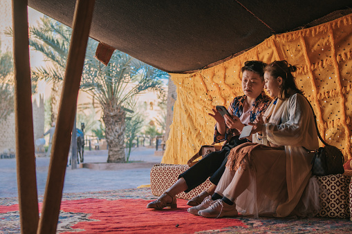 2 Chinese mature women relaxing in Bedouin tent camp in the desert oasis