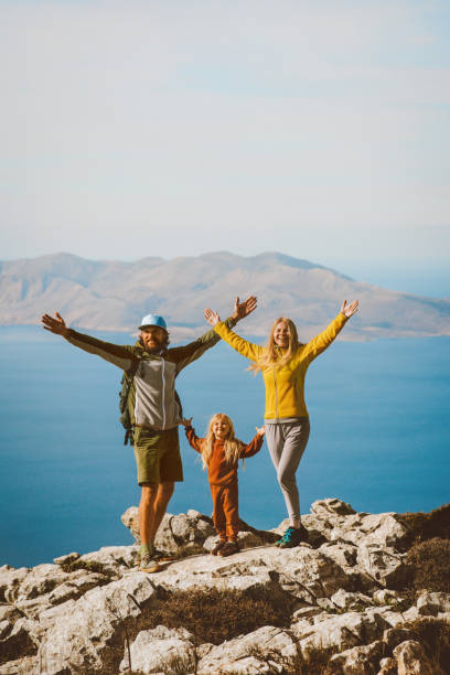 Family hiking in Greece parents with child travel outdoor mother and father raised hands active summer vacations healthy lifestyle eco tourism in Rhodes island mountain top stock photo