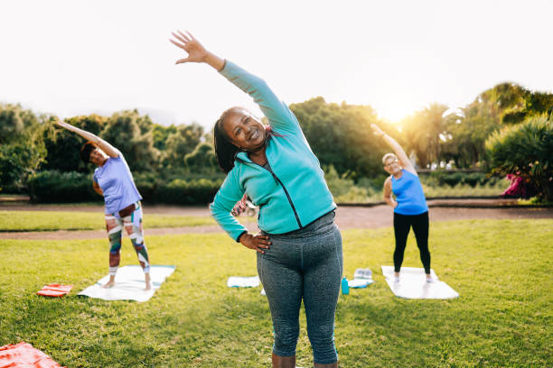 persone sportive senior che si esercitano durante la lezione di allenamento yoga all'aperto a park city - fitness gioioso stile di vita anziano - yoga exercising outdoors group of people foto e immagini stock