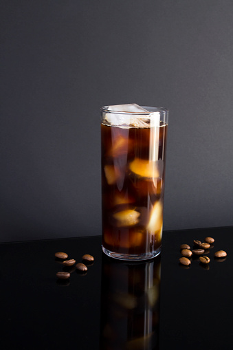 Cold brew coffee with ice in a tall glass on the dark background. Close-up.