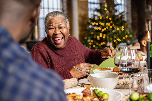 Happy and cheerful lady in her 60s enjoying a joke with her son in law at family meal