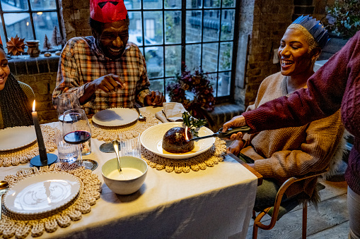 Black British family enjoying traditional lighting of the Christmas pudding