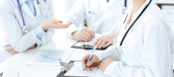 istock Group of unknown doctors discussing problems to stop coronavirus pandemic while sitting at meeting in clinic, close-up . Medicine concept 1478459804