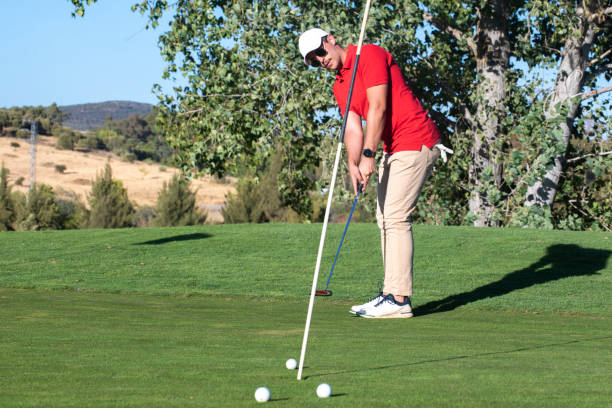 istock Golfer putting ball in the practice hole. Golf on the driving range shooting several golf balls at the flag. Golfer practicing his putt looking at the ball after the shot 1478461701