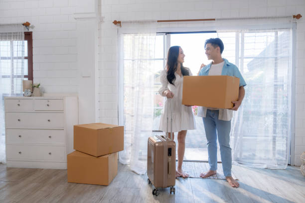 istock Asian couple carrying boxes into their new home on moving day. 1478463068