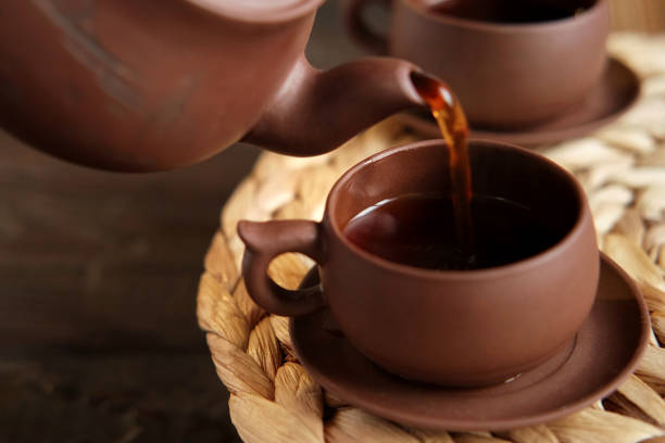Tea Ceremony. Traditional Asian Tea Utensil, Serving Authentic Set. Person Pouring Tea from Brown Pottery Teapot to Teacup. Bamboo Tray. Lifestyle. Wellness Balance Health. Tea Brewing Equipment