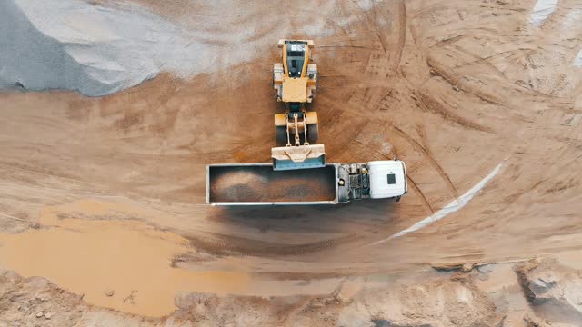 Loading crushed stone into a dump truck, aerial top view