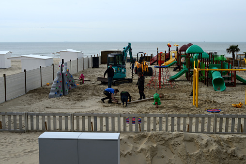 Blankenberge, West-Flanders, Belgium - March 29, 2023: four white men, workers installing after winter a complete playground attractions at a beach bar