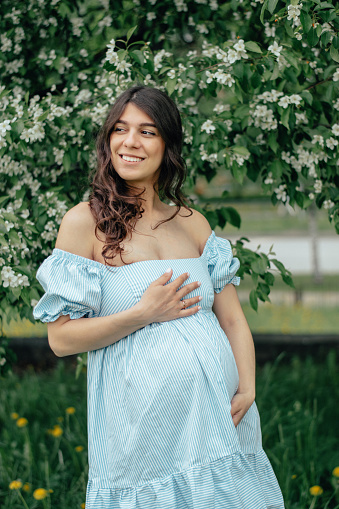 Portrait of a beautiful young pregnant woman in blooming apple trees.Spring,beauty,women's health concept.