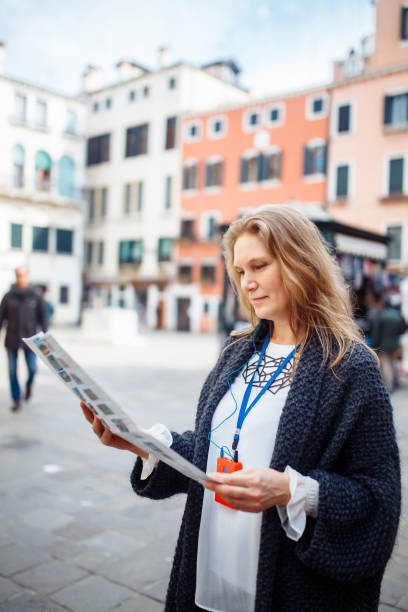 mature woman with map in venice, italy. beautiful woman having fun traveling outdoors during vacation in europe - travel outdoors tourist venice italy imagens e fotografias de stock