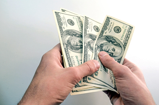 A person holds paper cash in his hands - counts, recalculates, pays, receives money.