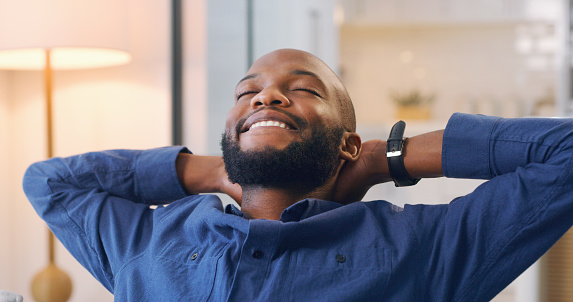 Relax, rest and happy black man in home on sofa with carefree, positive mindset and happiness. Weekend, peace and male with hands on head laying on couch for comfort, nap and lazy in living room