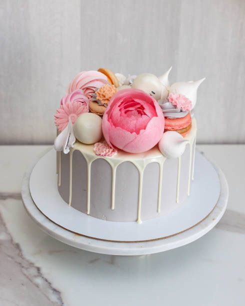 istock Beautiful and elegant grey cake decorated with melted white chocolate, macaroons, pink peony flower, cake pops and candies on marble cakestand 1478495374
