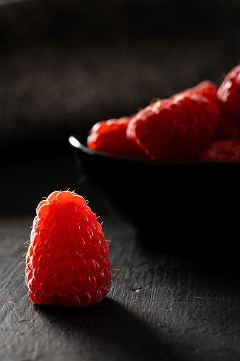 Fresh raspberries on a black rustic surface.