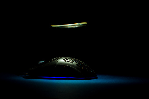black mouse with blue led with lighting effect black background and yellow lighting