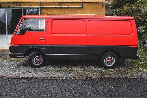 a minibus parked in front of a yellow building.