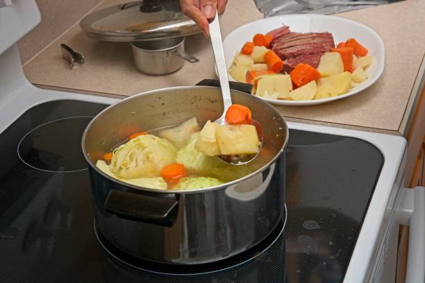 istock Ladling vegetables from simmering pot on stovetop  corned beef brisket on platter behind 1478503217