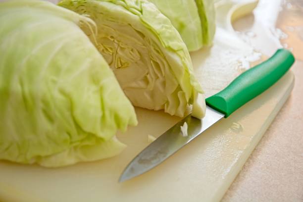 istock Close up quartered cabbage heads on cutting board paring knife. 1478503307