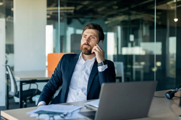 istock Confident middle aged businessman calling by cellphone, sitting at workplace with laptop and communicating in office 1478504482