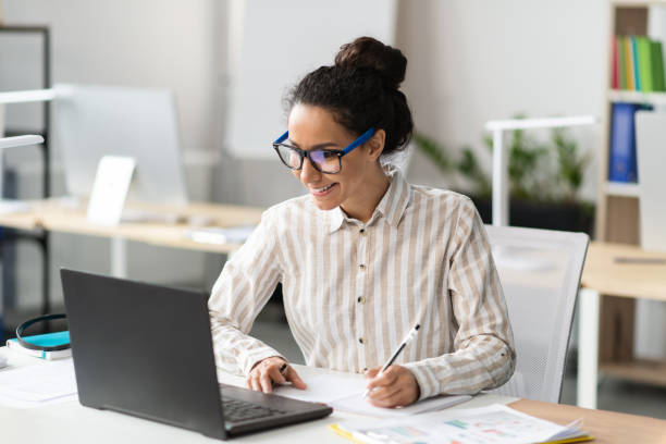 istock Happy young latin businesswoman working in office, sitting at workplace, using modern computer and taking notes 1478504507