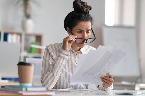 istock Female office manager wearing eyeglasses and doing paperworks, having eyesight problems, sitting at workplace 1478504508