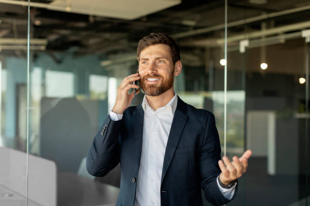 istock Successful caucasian businessman talking on smartphone, standing in office interior, having phone talk 1478505207