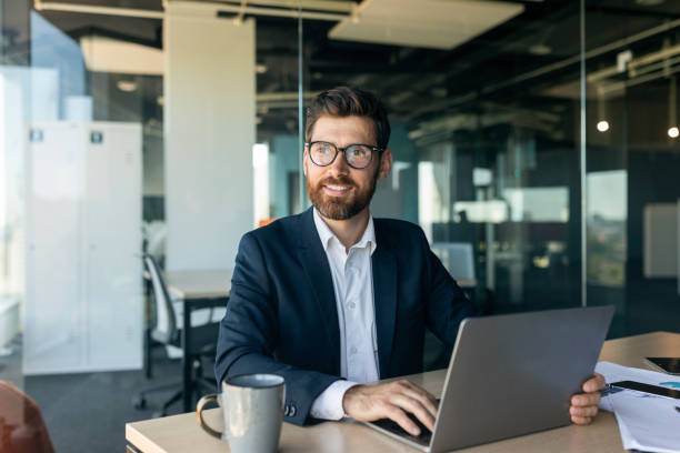 istock Mature male entrepreneur using laptop and thinking, looking aside while sitting at workplace in office, free space 1478505407