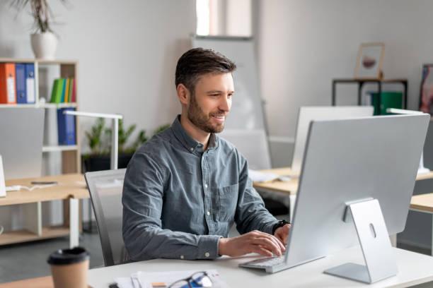 istock Cheerful middle aged businessman sitting at worktable, typing on computer keyboard, working on marketing research 1478505522