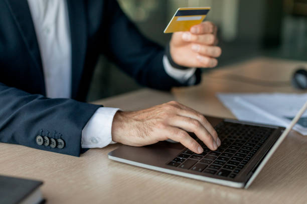 istock Male entrepreneur using credit card and laptop while sitting at workplace in office, focus on hand on keyboard 1478505637