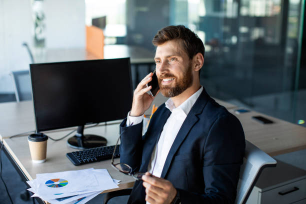 istock Happy middle aged businessman having conversation on mobile phone, using computer with blank screen, mockup 1478505831