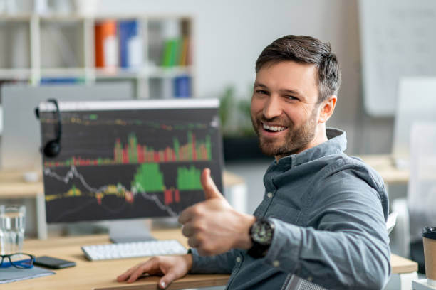 istock Happy mature businessman working on computer with graphs and charts, sitting in office and showing thumb up 1478505865