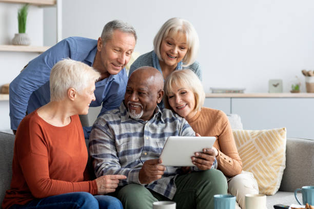 istock Cheerful elderly people spending time together at home, using gadgets 1478506026